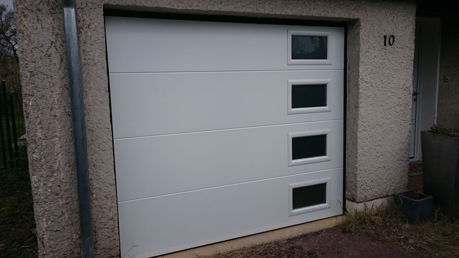 Pose d'une porte de garage sectionnelle avec panneaux acier et hublots rectangulaires  - 38 Diémoz